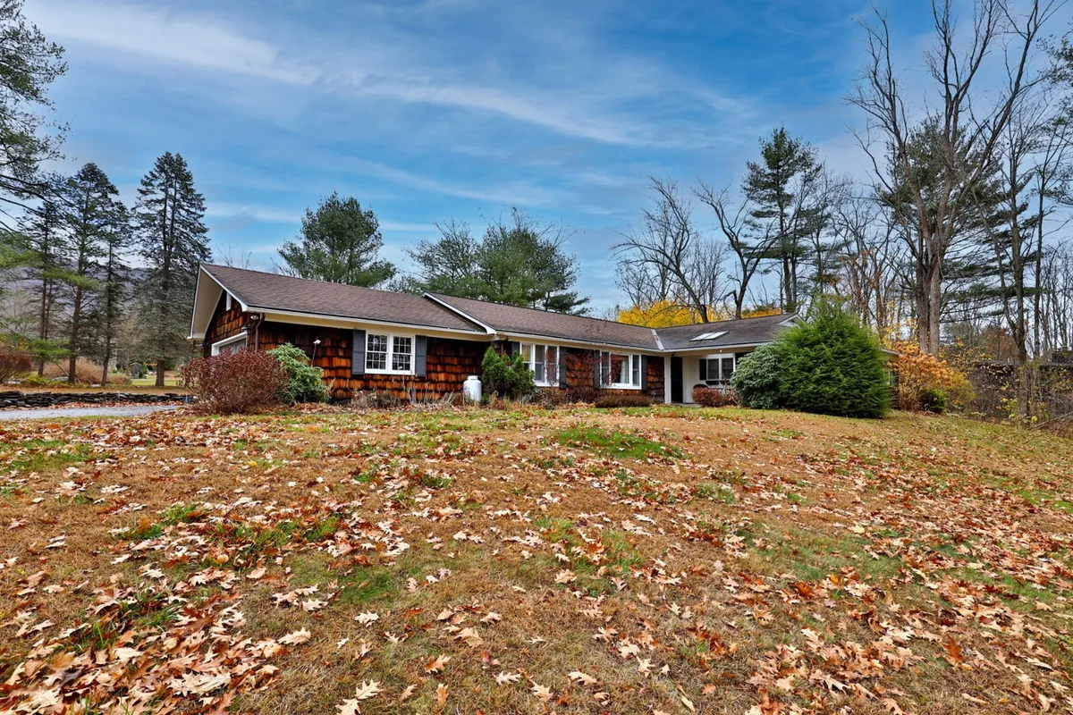The home’s wooden exterior is surrounded by a tranquil front yard and towering trees, evoking the four-season charm of Vermont. There's ample space for lawn games, family picnics, or simply enjoying the mountain sunset.