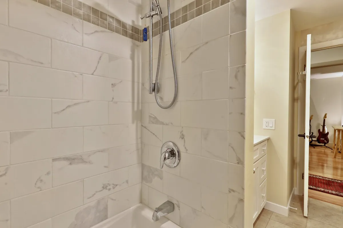 A tranquil bathroom scene showing a shower head, marble tile, and a bathtub. The elegant finishes and spa-like ambiance invite relaxation after a long day, complementing the soothing mood described in the section.