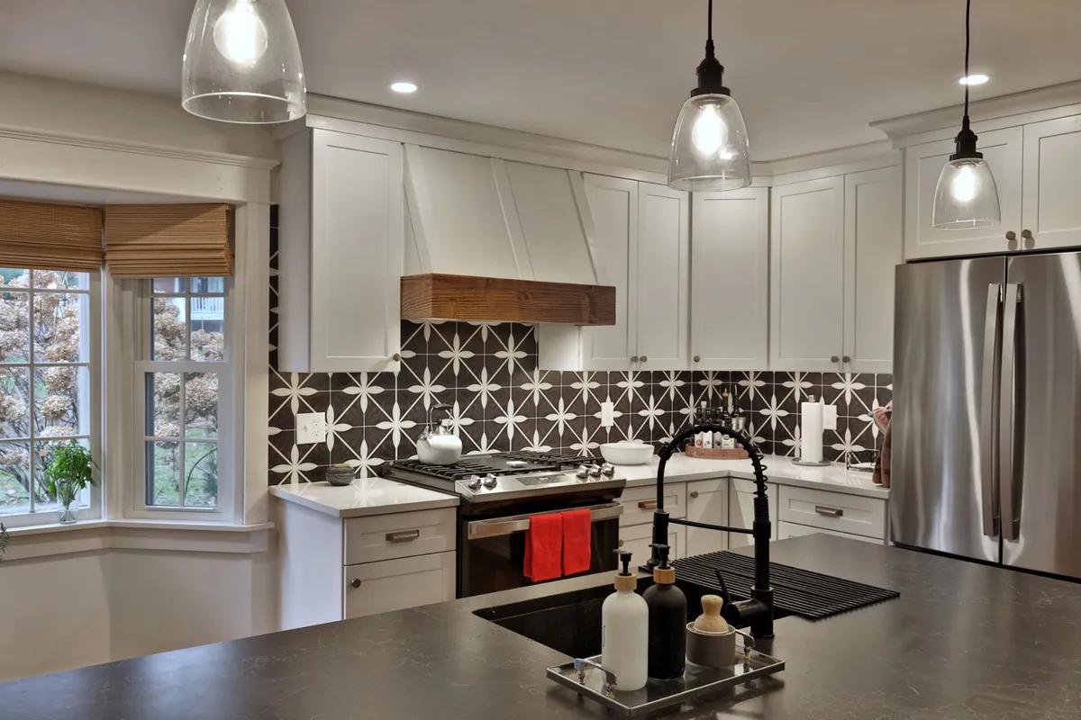 A contemporary kitchen shines with a spacious island, decorative backsplash, stainless steel appliances, and pendant lighting. The area is stylish yet functional, inviting culinary creativity and conversation.