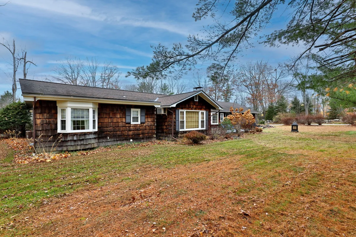 This exterior shot features the home’s weathered wood siding, large windows that connect the indoors to the natural surroundings, and a manicured lawn framed by mature trees. The setting evokes both seclusion and access to the outdoors, suggesting plenty of space for family gatherings, outdoor games, and easy access to nearby trails and mountains.